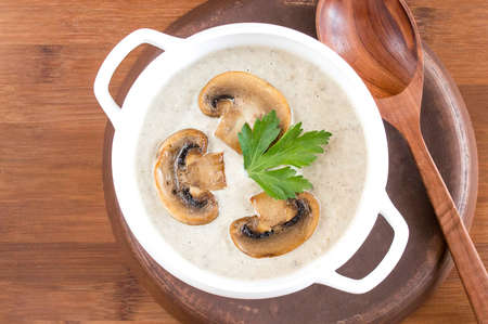 Potato cream soup with mushrooms. Wooden background, a large spoon. Portion plate.の写真素材