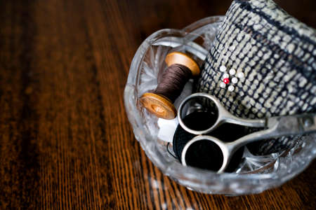 Tools for darning clothes. Scissors, spool of thread and pins in a crystal vase. Place for textの写真素材