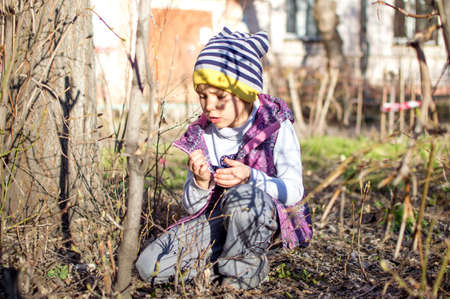 Girl walks in the yard in spring. Look for the beetle, consider it. Surprise plantsの写真素材