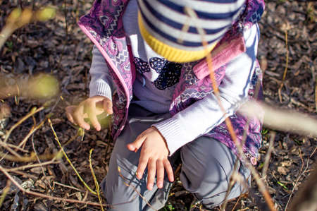 Girl walks in the yard in spring. Look for the beetle, consider it. Top viewの写真素材