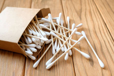 Cotton buds are scattered on a wooden background. Eco-friendly cotton earplugsの写真素材