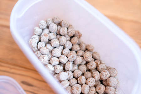 Bran in a plastic container. Dry edible balls. Wood backgroundの写真素材