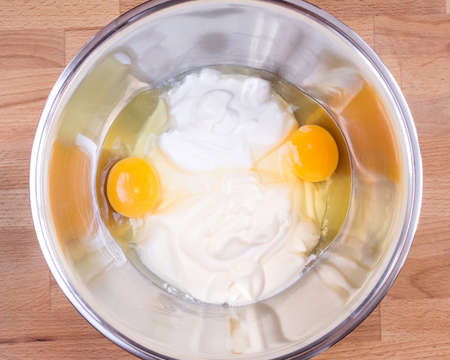 Sour cream, mayonnaise, raw eggs in a bowl. Ingredients for making pie doughの写真素材