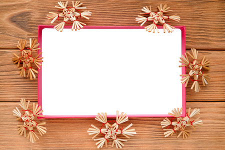 The white rectangle is surrounded by straw snowflakes. Warm wood backgroundの写真素材