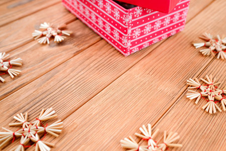 New Year card on a wooden background. Red box. Straw toy snowflakesの写真素材