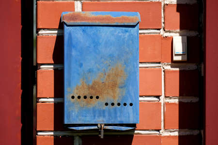 A blue mailbox hangs on a red brick wall outside. Russian post box.の写真素材