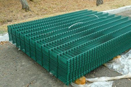 Green metal fence sheets lie on the asphalt.の写真素材