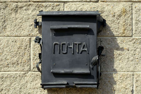 A black metal mailbox hangs on the wall of the house. Russian word: mail.の写真素材