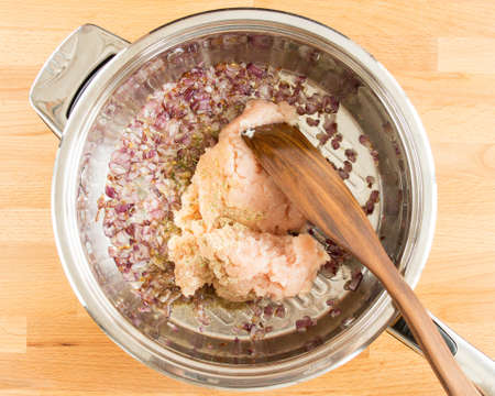 Fried onions and raw chicken are mixed in a frying pan. Without people.の写真素材