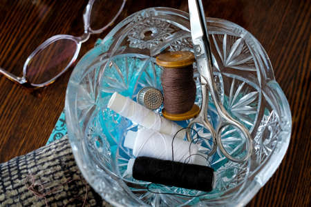 Crystal vase with spools of thread and scissors. Grandma's items.の写真素材