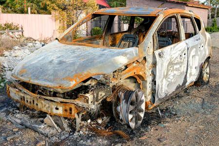 The burned-out car is parked on the street. No people. Sunset.の写真素材