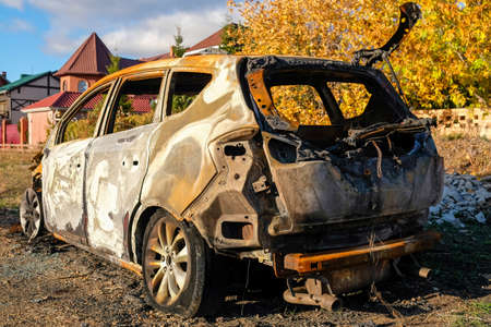 Burned-out car stands on the street in autumnの写真素材