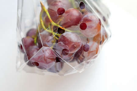 Grapes in transparent plastic packaging on a light backgroundの写真素材