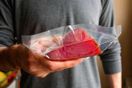 Holds a piece of tuna in a package in his hand.の写真素材