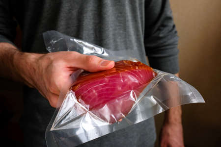 Tuna in the package. A man holding a packed red fish in his hand.の写真素材