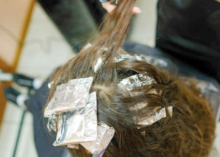 Dyed strands of hair are wrapped in foil bags. Hair coloring processの写真素材