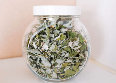Dry raspberry grass in a large glass jar stands on a white shelf.の写真素材