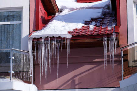Large long icicles hang under the roof of the building.