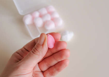 Wax ball earplugs knead fingers. The storage box is visible in the background.の写真素材