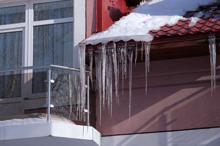 Icicles under the roof of the house. Spring bright long transparent icicles.の写真素材