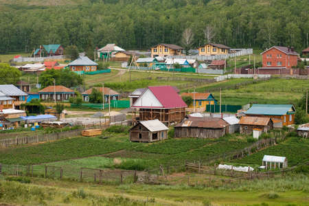 Bashkiria, 06.26.2021 - Village in summer, houses, fields and outbuildings are visible.