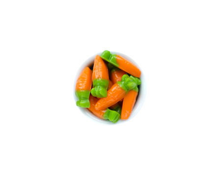 Marmalade in the form of carrots in a bowl in the center of a white backgroundの写真素材