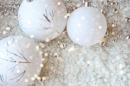Decor for a happy Christmas and New year. Silver color. Christmas balls and beads on a white cozy blanket. happy winter holidays. Background for congratulations. White balls for Christmas tree decoration.の写真素材