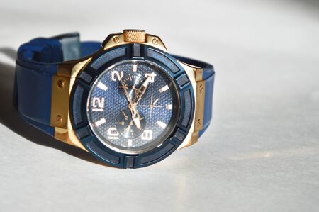 Stylish blue wrist watch on a white background. Round dial in blue and gold colors.の写真素材