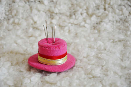 a sewing needle in a pink pillow-hat on a white background. tools for creativity and needlework.の写真素材