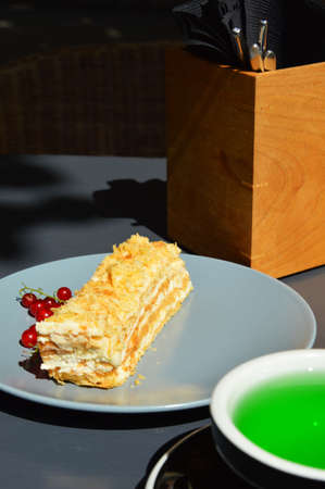 cream pie and red berries. delicious piece of cake. green tea in a black Cup. a teaspoon and a mug...