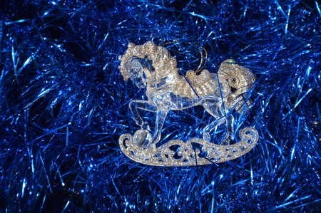 Blue tinsel for a festive Christmas tree and a toy in the form of a horse for decoration for the new year and happy Christmas. background for the design.の写真素材