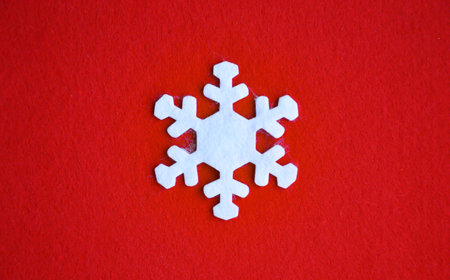 white felt snowflake on a red background. Decoration for Christmas and New Year. Winter holidays.の写真素材