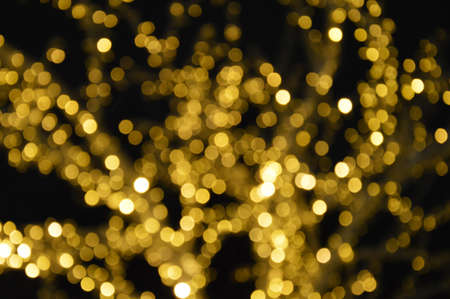 the bokeh lights are yellow. Festive shiny background for celebrating Merry Christmas and Happy New...