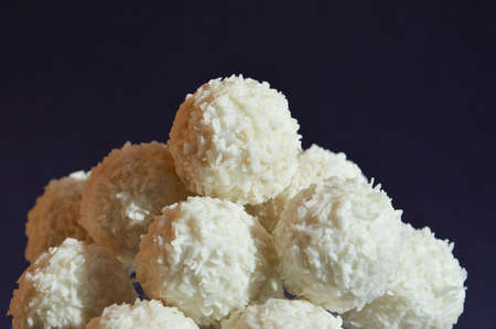 coconut balls. delicious candies with coconut chips. sweet dessert on a dark blue background.