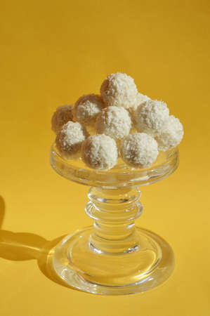 coconut balls. delicious candies with coconut chips. sweet dessert on a yellow background.