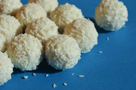 coconut balls. delicious candies with coconut chips. sweet dessert on a blue background.