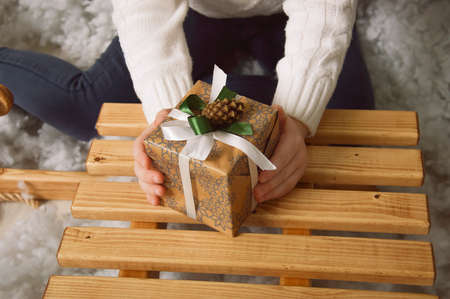 a girl holds a gift box on a wooden sleigh. Merry Christmas and Happy New Year.