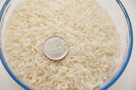 rice grits and 1 ruble in a glass plate. healthy porridge. vegetarian food. rice for roubles.