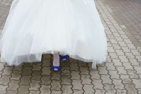 the bride in a white wedding dress and blue shoes. feet in shoes. background for the design.の写真素材