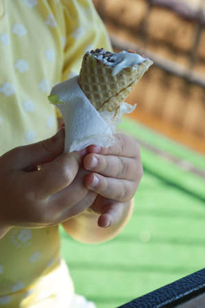 a child eat ice cream. a waffle cone in children's hands. sweet food. background for the design.の写真素材