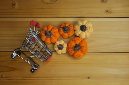 orange knitted pumpkins in a grocery cart. preparing for Halloween. autumn background for decoration. buying vegetables.の写真素材