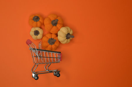 orange knitted pumpkins in a grocery cart. preparing for Halloween. autumn background for decoration. buying vegetables.の写真素材