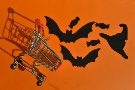 preparation for the Halloween holiday. bat and candy and felt on an orange background. shopping cart. autumn.の写真素材