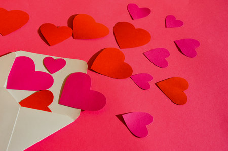 Valentine's day background with red paper hearts and envelope on red backgroundの写真素材