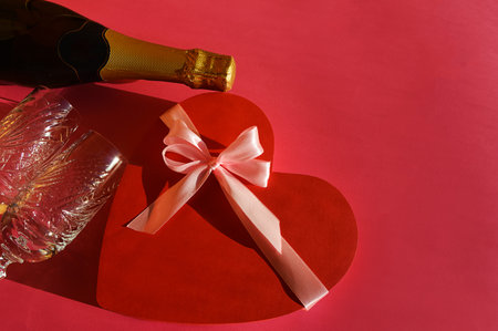 Valentine's day background. Champagne bottle, heart and gift box on red backgroundの写真素材