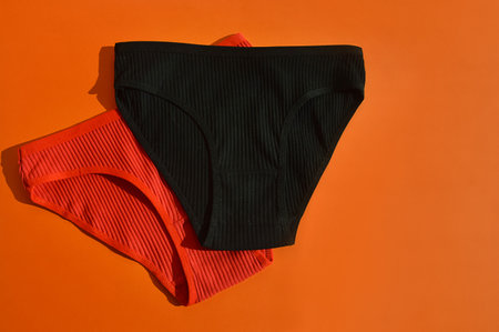 Women's panties on an orange background. Flat lay, top view.