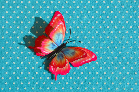 Red butterfly on blue polka dot background with space for text.