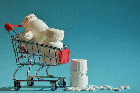 Shopping cart full of pills and bottles on blue background. Focus on foreground.の写真素材