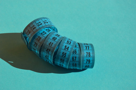 Blue measuring tape on a turquoise background. The concept of weight loss.