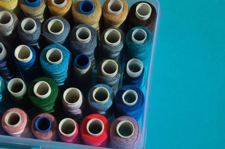 Colorful thread spools in plastic box on blue background. close up.の写真素材